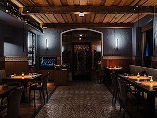 Elegantes Restaurantinterieur mit Holzbalkendecke, Stimmungsbeleuchtung und Weinauslage