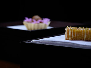 Nahaufnahme eines Desserts mit Karamellguss auf Serviette, unscharfer Cupcake im Hintergrund