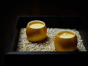 Gourmet-Eiercreme in Eierschalen auf einem Bett aus Getreide in dunklem Holztablett