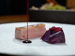 Gebratene Entenbrust mit Rotweinsauce und violettem Gemüsegarnitur auf weißem Teller