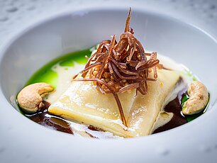Gourmet-Ravioli in grüner Sauce mit frittierten Streifen und Cashewkernen